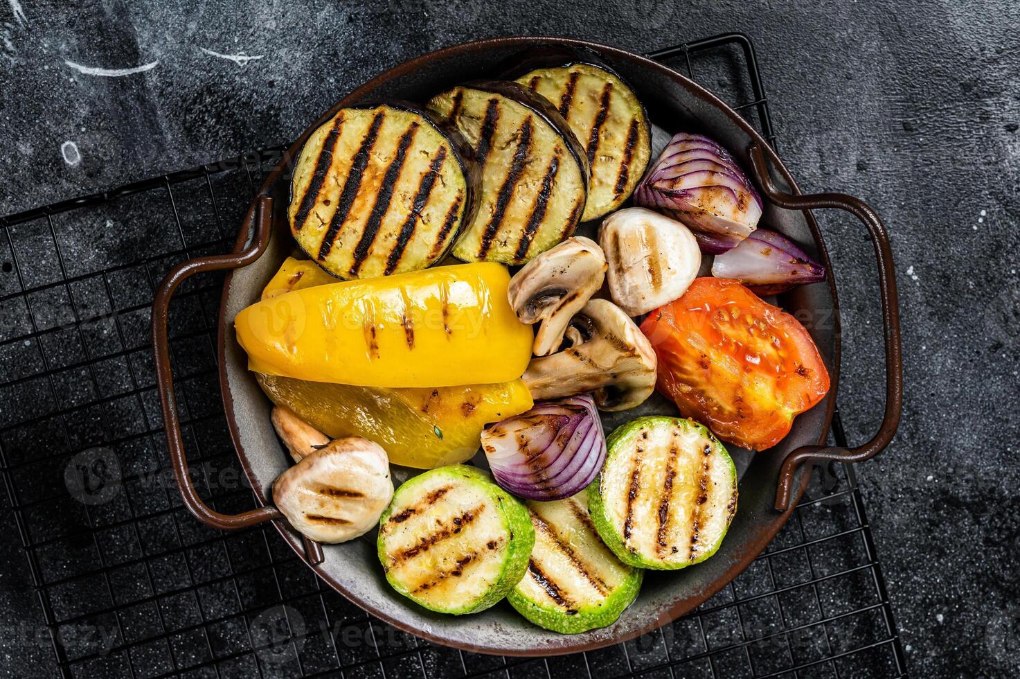 Grilled vegetables, bell pepper, zucchini, eggplant, onion and tomato. Black background. Top view photo