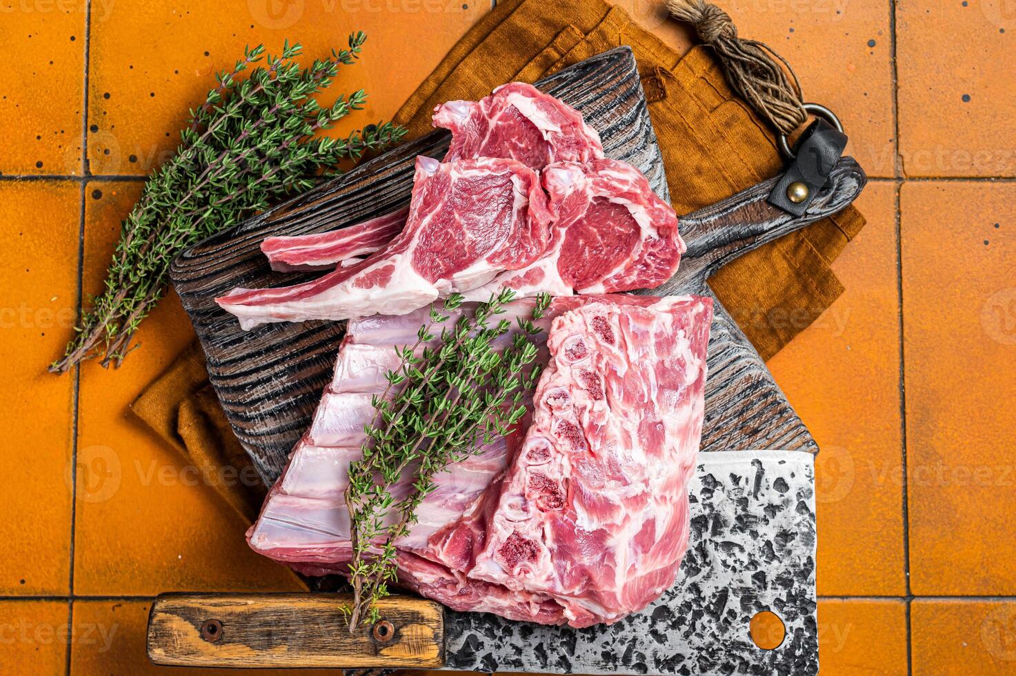 Raw lamb meat chops cutlets on butcher cutting board. Orange background. Top view photo