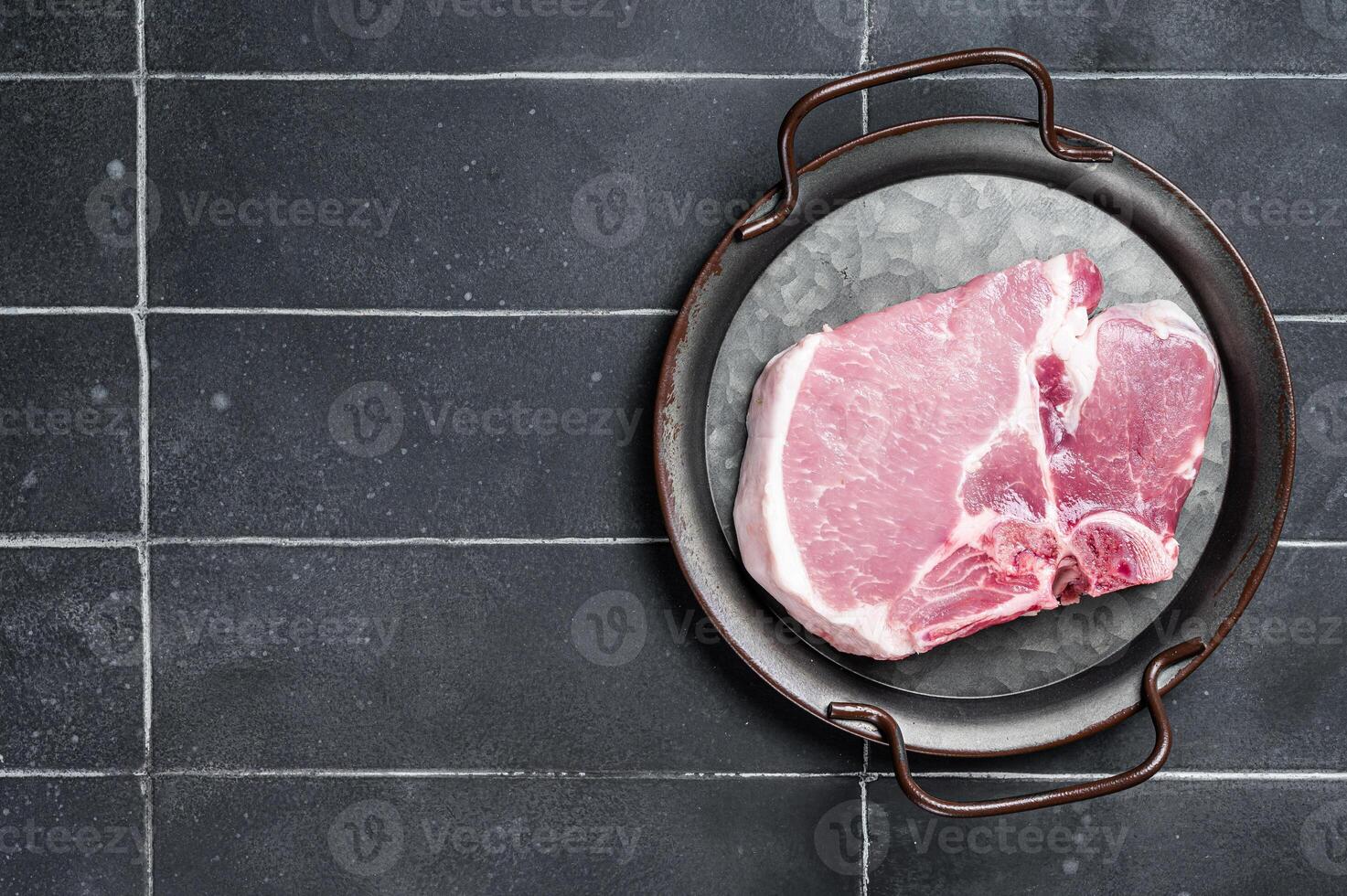 Raw pork t bone chop meat steak. Black background. Top view. Copy space photo