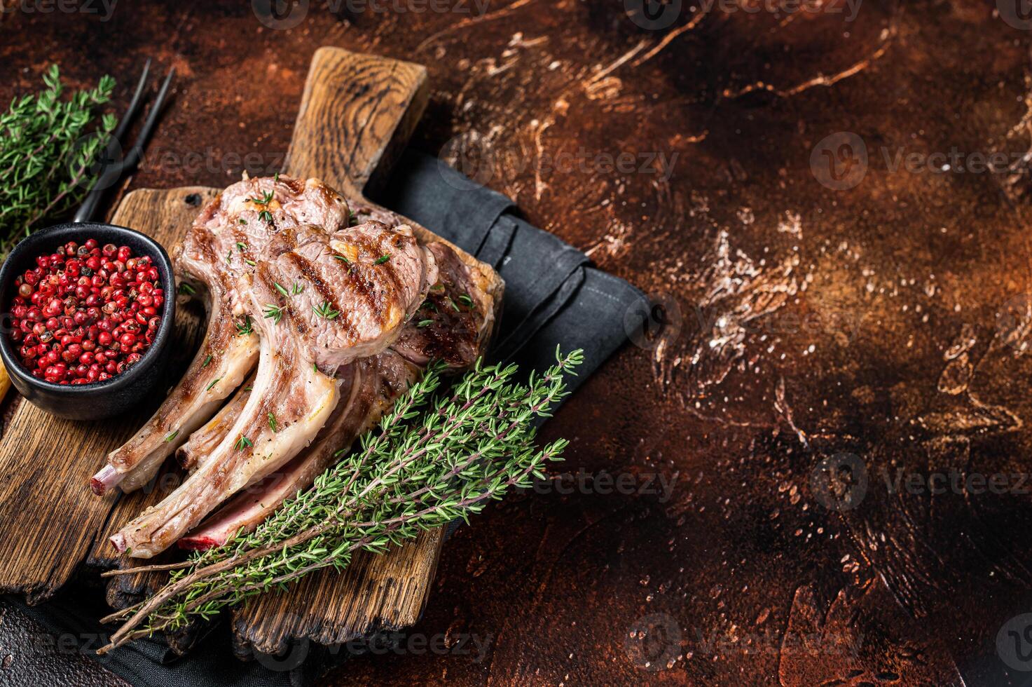 Grilled New Zealand Lamb Chops, mutton cutlets on wooden board. Dark background. Top view. Copy space photo