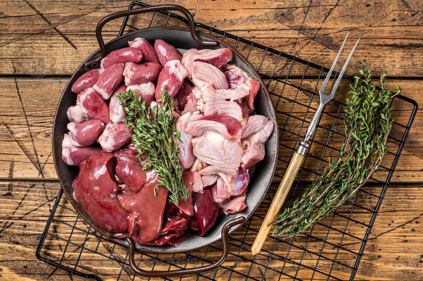 Raw bird giblets meat set, chicken offals, liver, hearts, gizzards Stomach. Wooden background. Top view photo