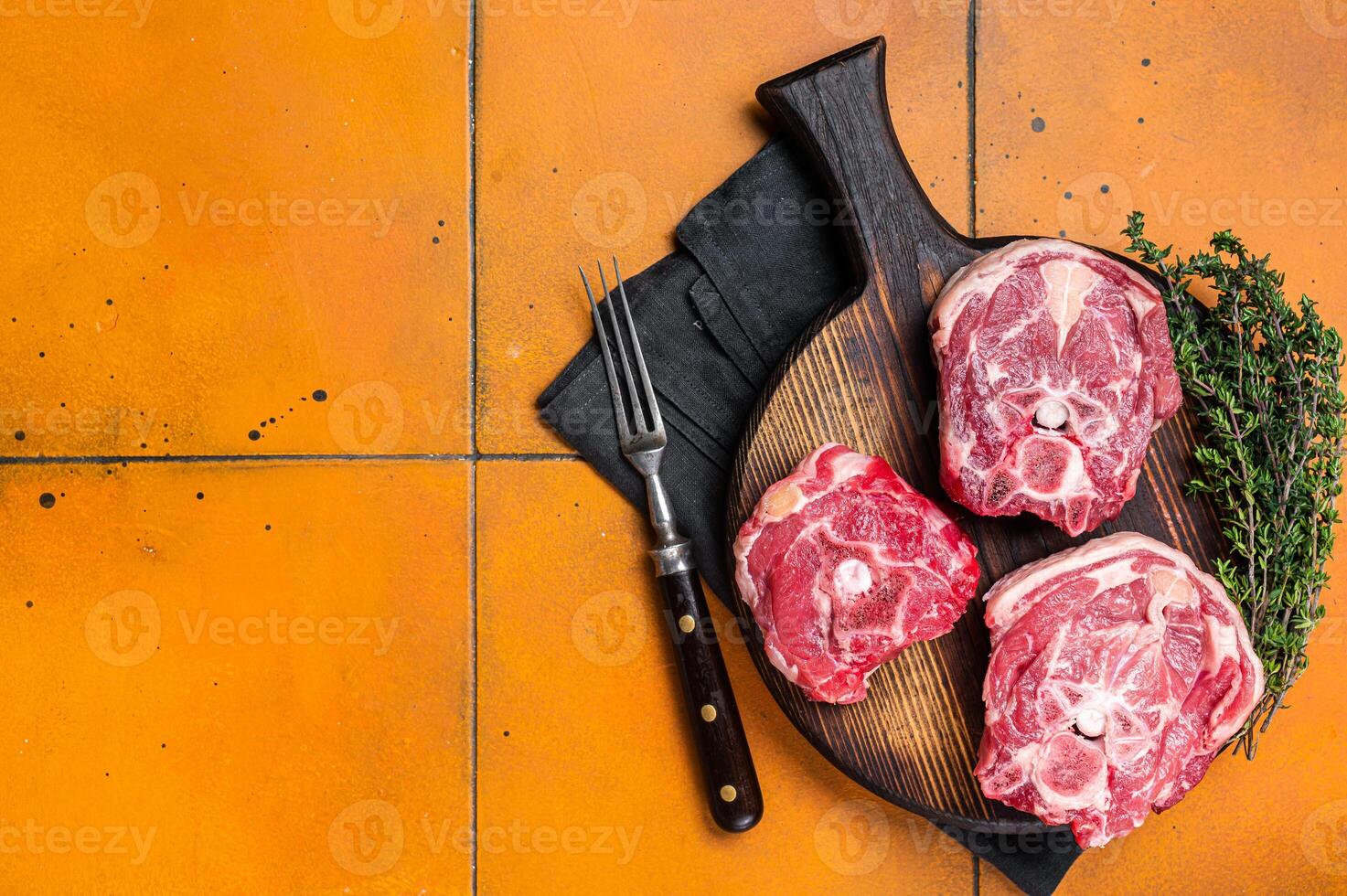 Raw lamb neck chops, fresh mutton meat on a butcher board with herbs. Orange background. Top view. Copy space photo
