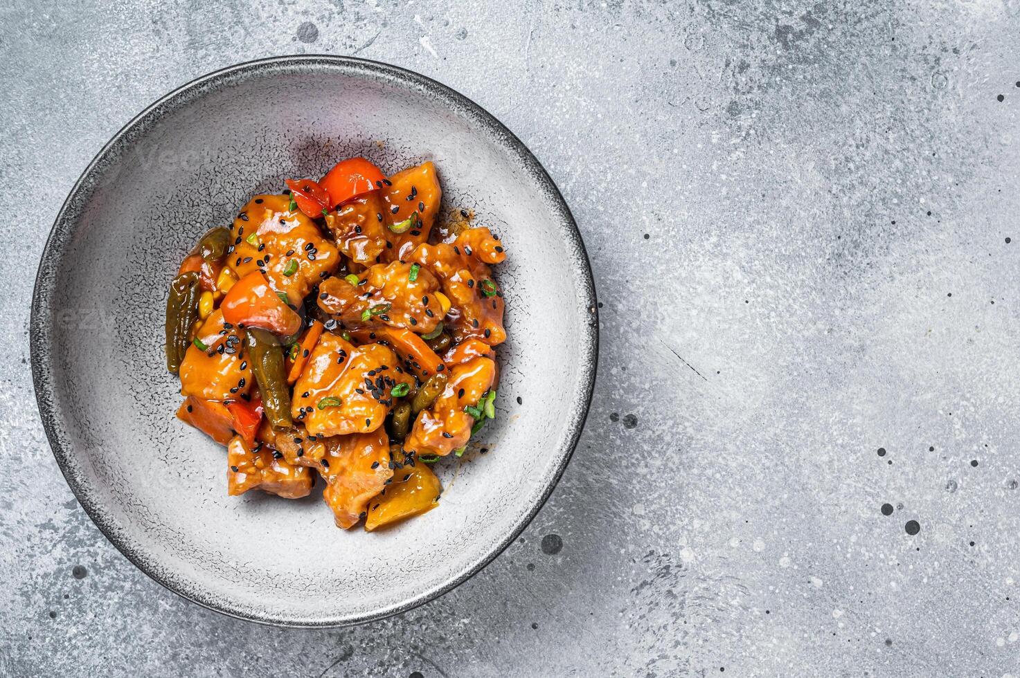 Chinese Sweet and Sour Pork guo bao rou in a bowl. Gray background. Top view. Copy space photo
