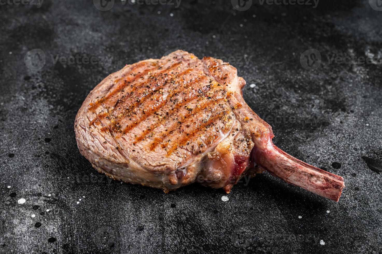 BBQ Grilled Tomahawk beef veal steak on butcher table. Black background. Top view photo