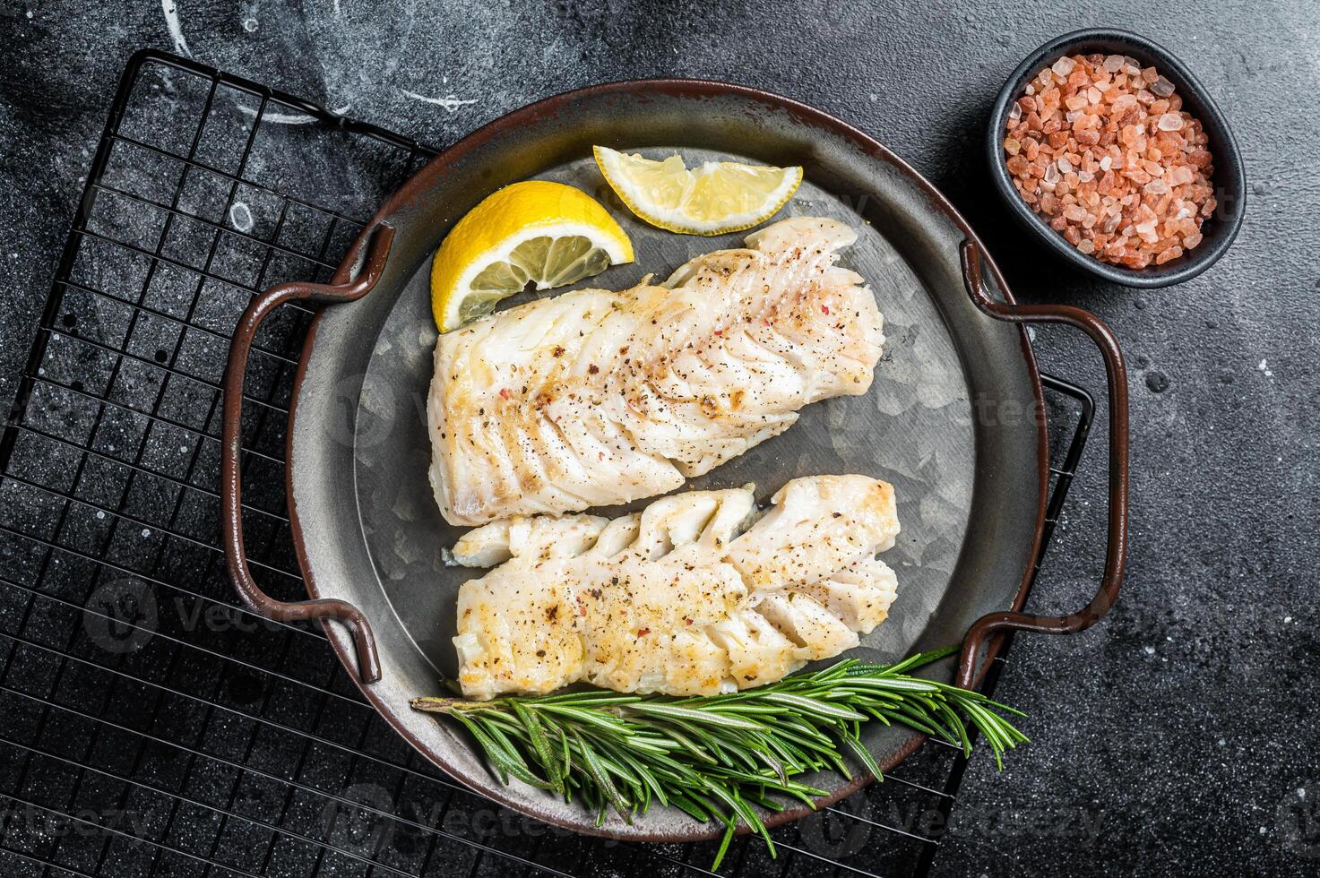 Roast Fillets of codfish, cooked cod fish meat. Black background. Top view photo
