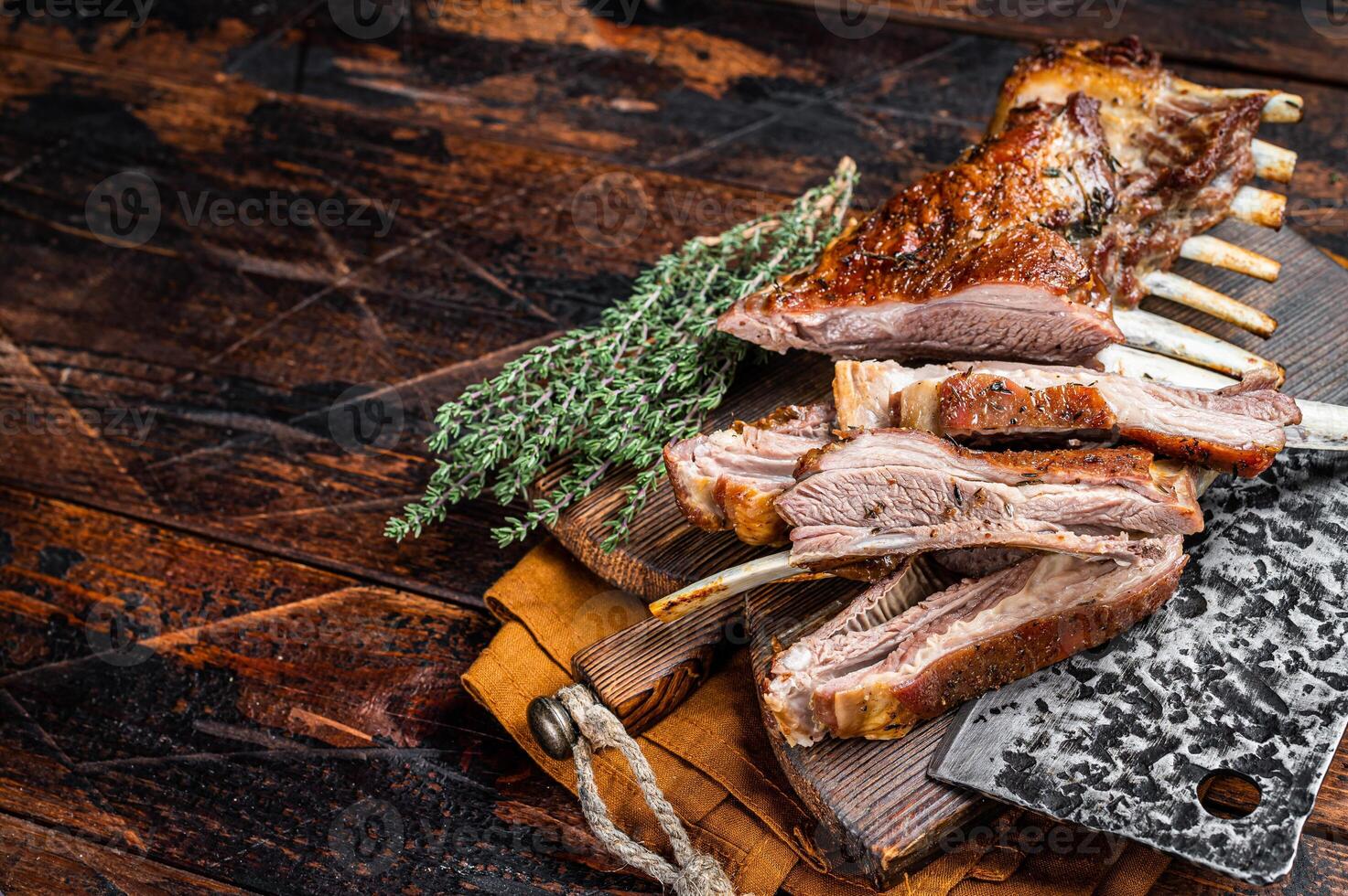 Roast lamb ribs, mutton spareribs, sliced meat on wooden board. Wooden background. Top view. Copy space photo