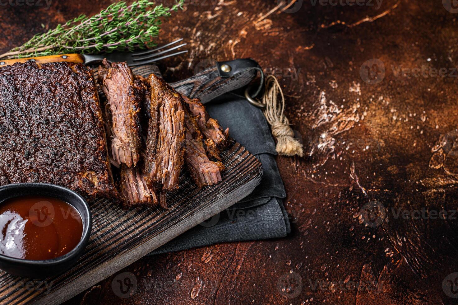 Traditional smoked barbecue wagyu beef brisket on wooden board. Dark background. Top view. Copy space photo
