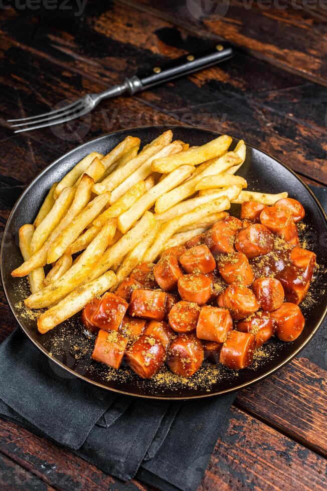German currywurst meal, curry wurst with french fry served in a plate. Wooden background. Top view photo