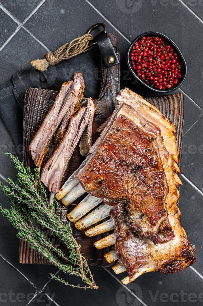 Grilled Rack of lamb ribs, mutton spareribs on wooden board. Black background. Top view photo