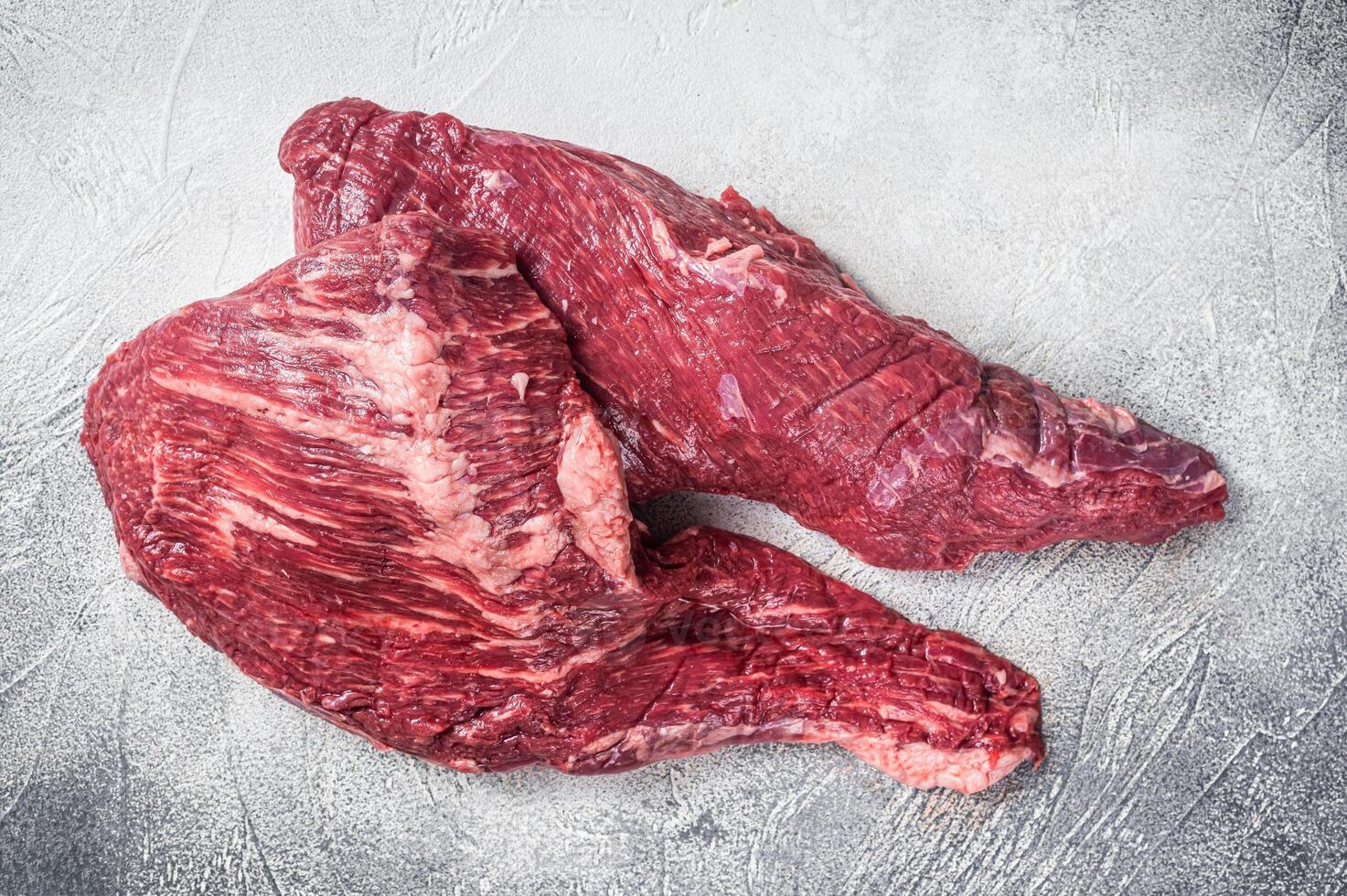 Raw tri tip beef steak on kitchen table. White background. Top view photo