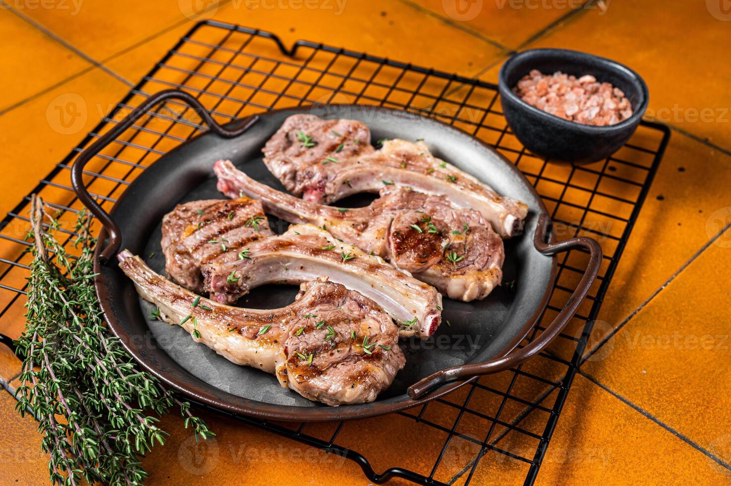 BBQ with Grilled lamb meat chops, mutton steaks with herbs. Orange background. Top view photo