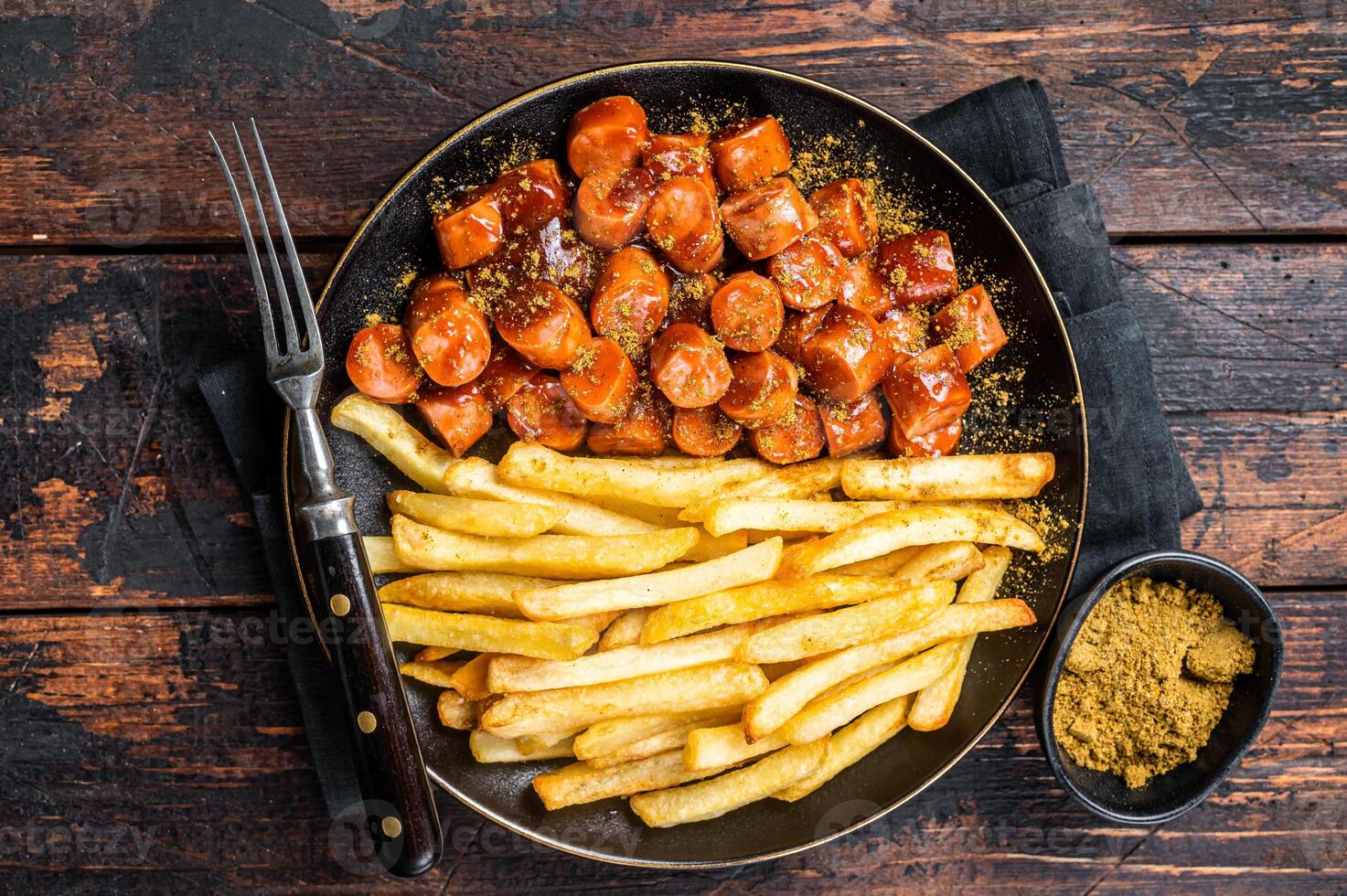 German currywurst meal, curry wurst with french fry served in a plate. Wooden background. Top view photo