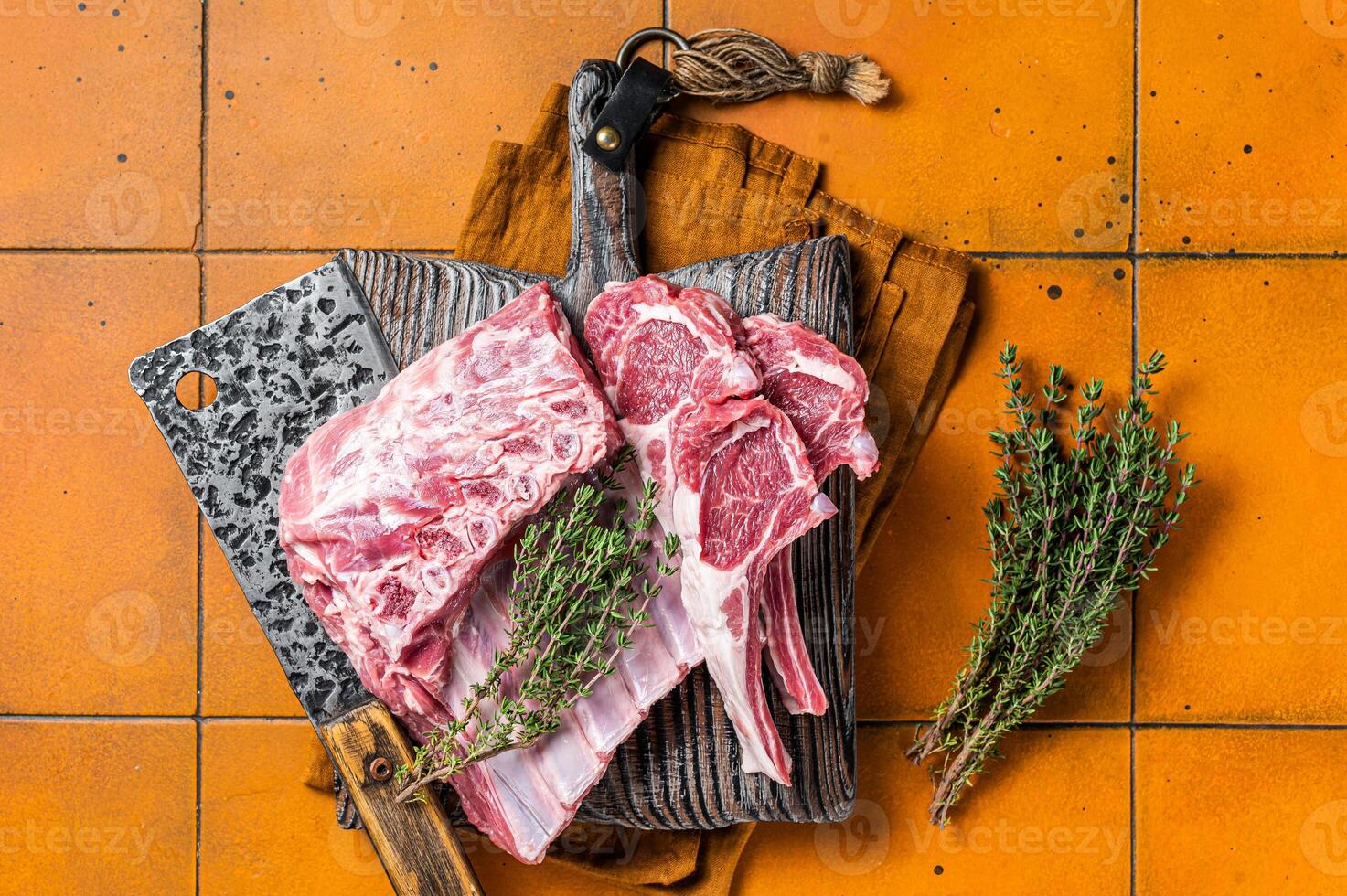 Raw lamb meat chops cutlets on butcher cutting board. Orange background. Top view photo