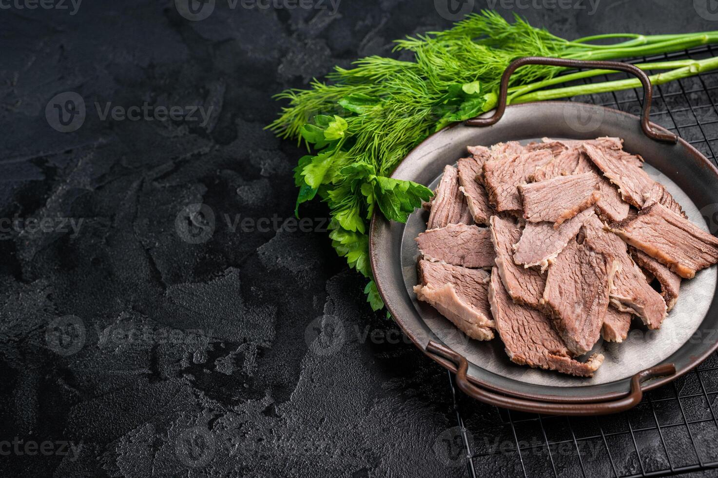 Boiled sliced beef meat in a steel tray. black background. top view photo