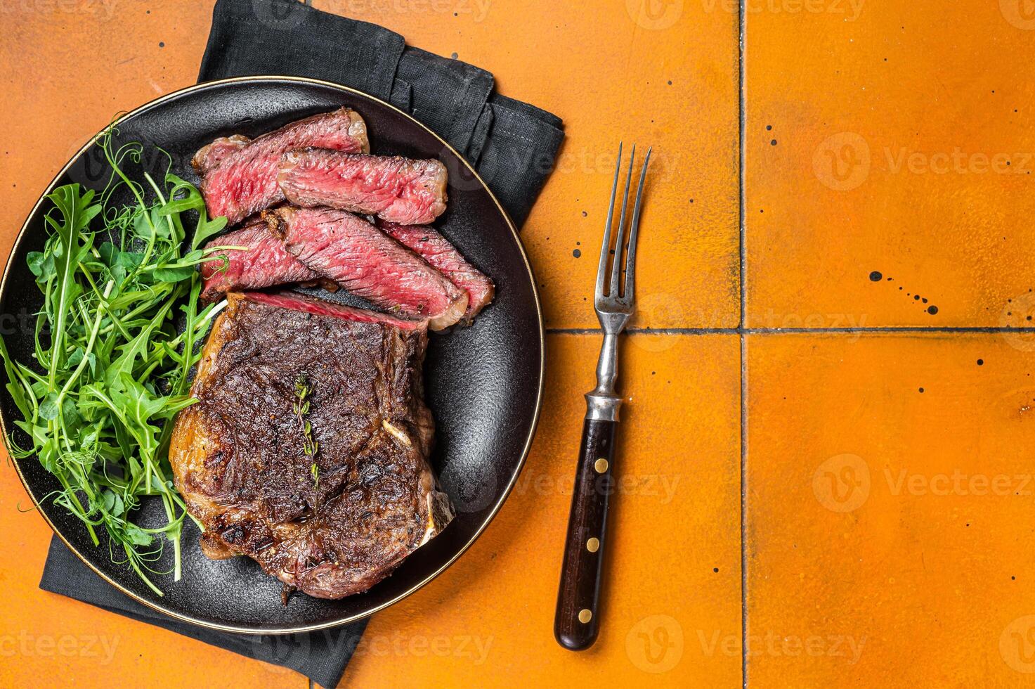 BBQ Grilled Wagyu New York beef meat steak or Striploin steak in a plate with salad. Wooden background. Top view. Copy space photo