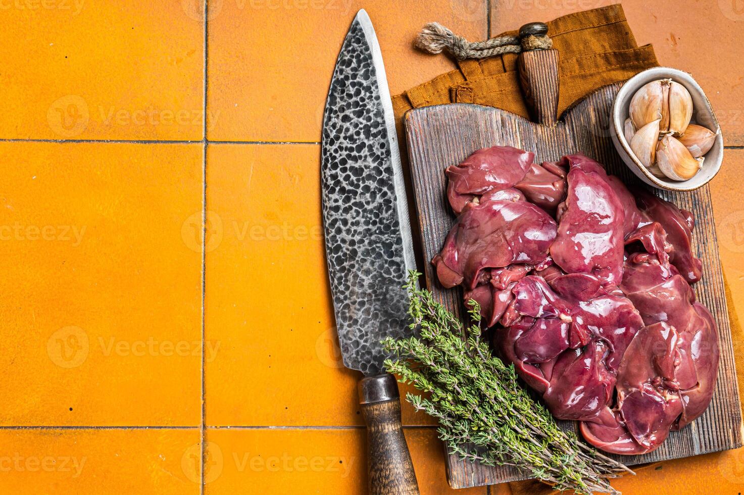 Raw chicken liver, fresh fowl giblets on wooden board. Orange background. Top view. Copy space photo