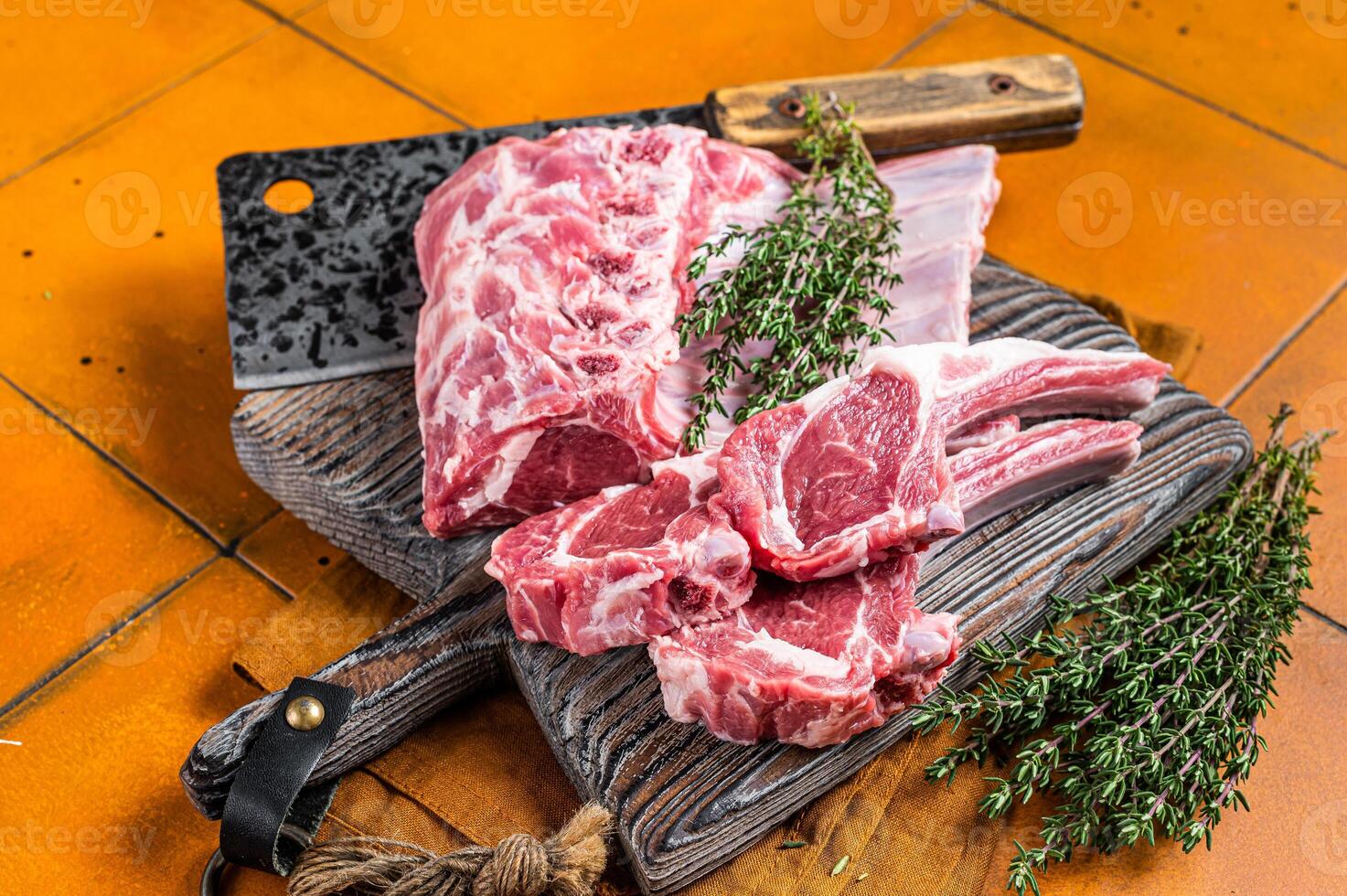 Raw lamb meat chops cutlets on butcher cutting board. Orange background. Top view photo