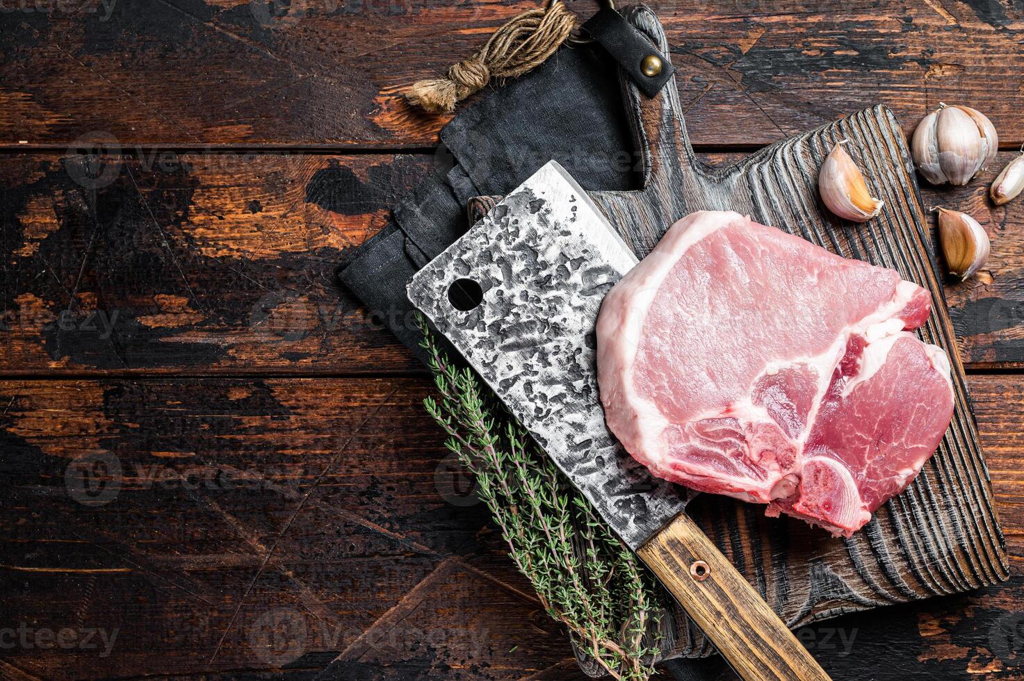 Butcher cutting board with Raw T-bone pork chop meat steak. Wooden background. Top view. Copy space photo