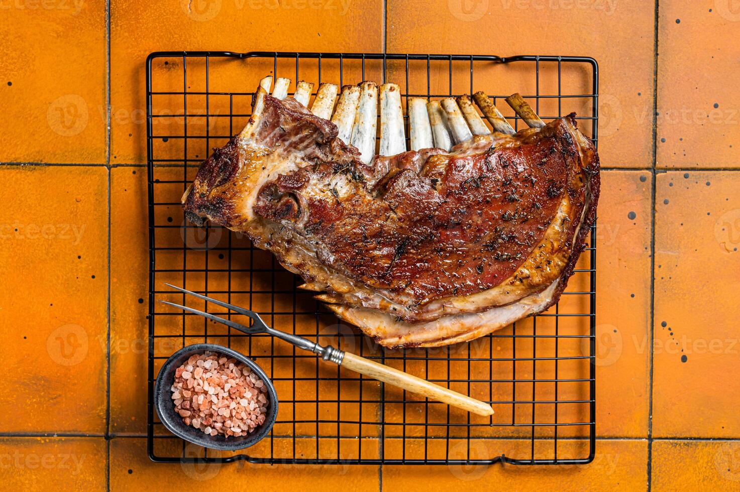 Roast Rack of lamb ribs, spareribs on grill. Orange background. Top view photo