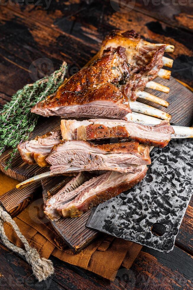 Roast lamb ribs, mutton spareribs, sliced meat on wooden board. Wooden background. Top view photo