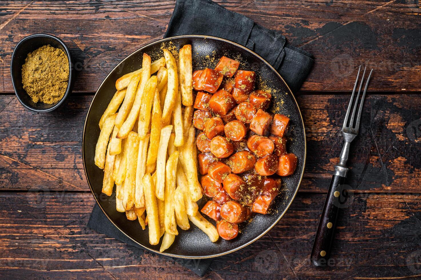 German currywurst meal, curry wurst with french fry served in a plate. Wooden background. Top view photo