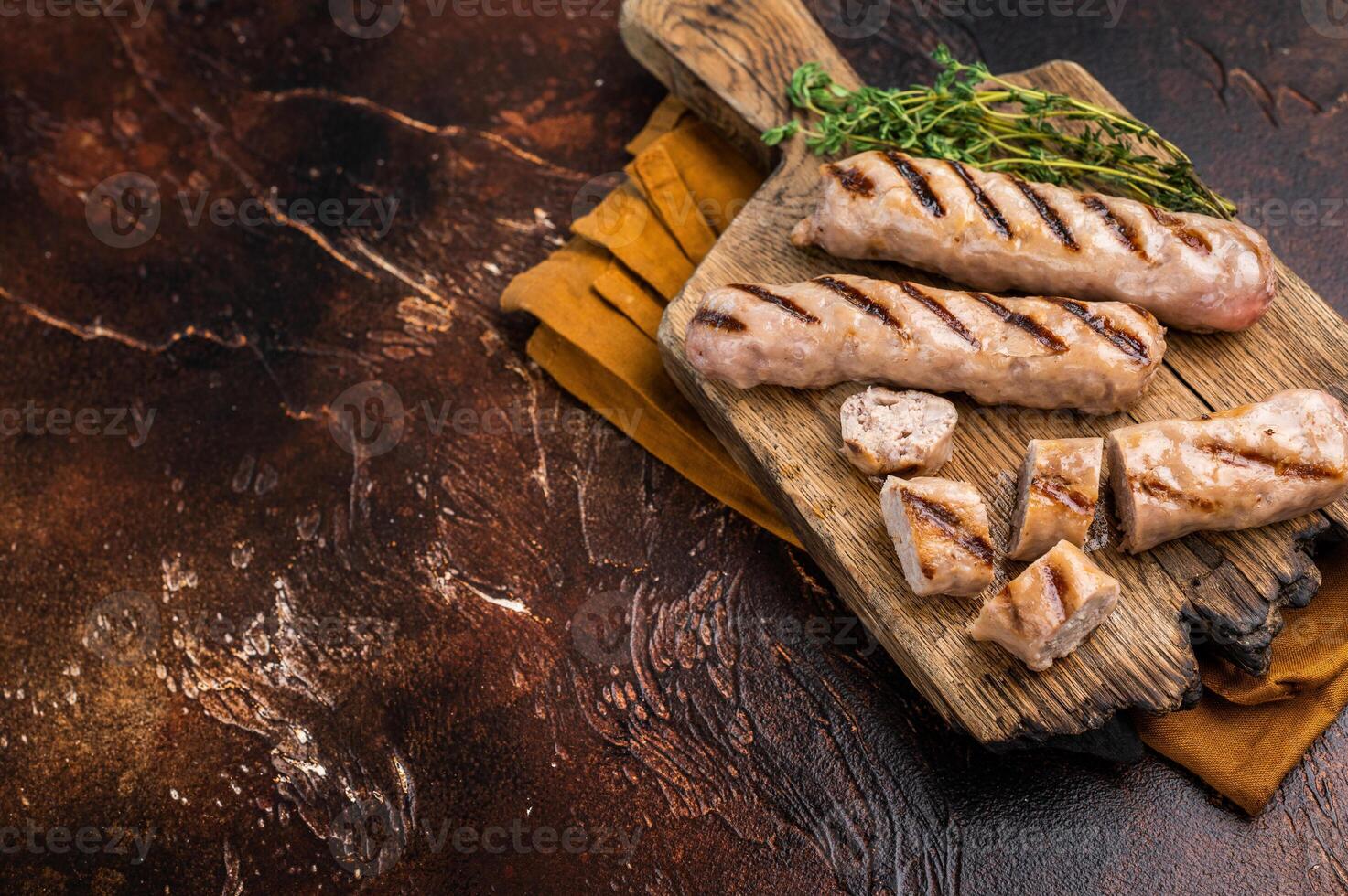 Fried on BBQ beef and pork sausages on wooden cutting board. brown background. top view photo