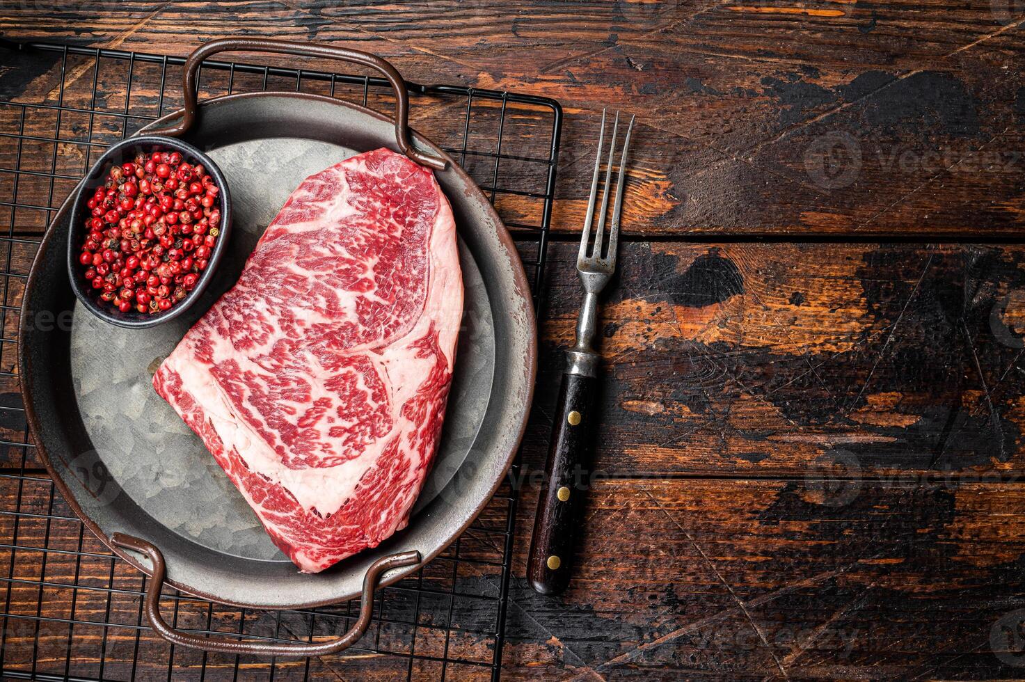 Raw wagyu rib eye beef meat steak in steel tray. Wooden background. Top view. Copy space photo