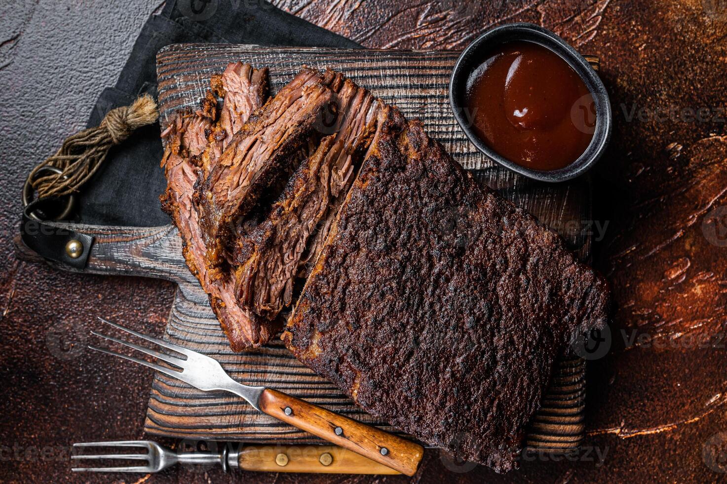 Traditional smoked barbecue wagyu beef brisket on wooden board. Dark background. Top view photo