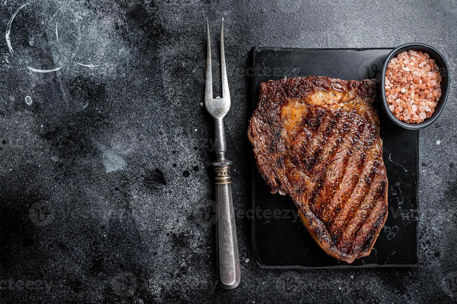 Grilled wagyu Rib Eye steak, marbled beef meat with salt. Black background. Top view. Copy space photo