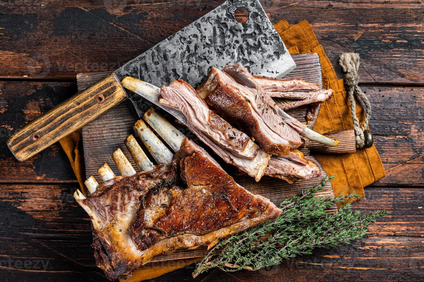Roast lamb ribs, mutton spareribs, sliced meat on wooden board. Wooden background. Top view photo