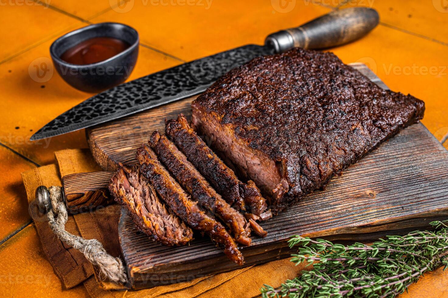 Smoked Barbecue Beef Brisket with Sauce on wooden board. Orange background. Top view photo