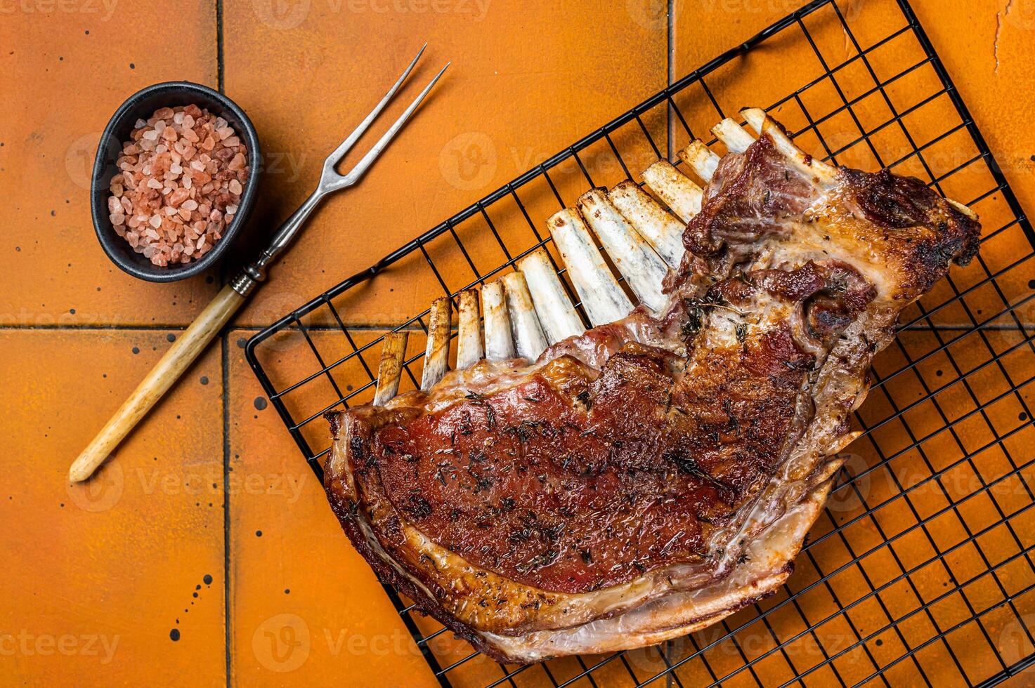 Roast Rack of lamb ribs, spareribs on grill. Orange background. Top view photo