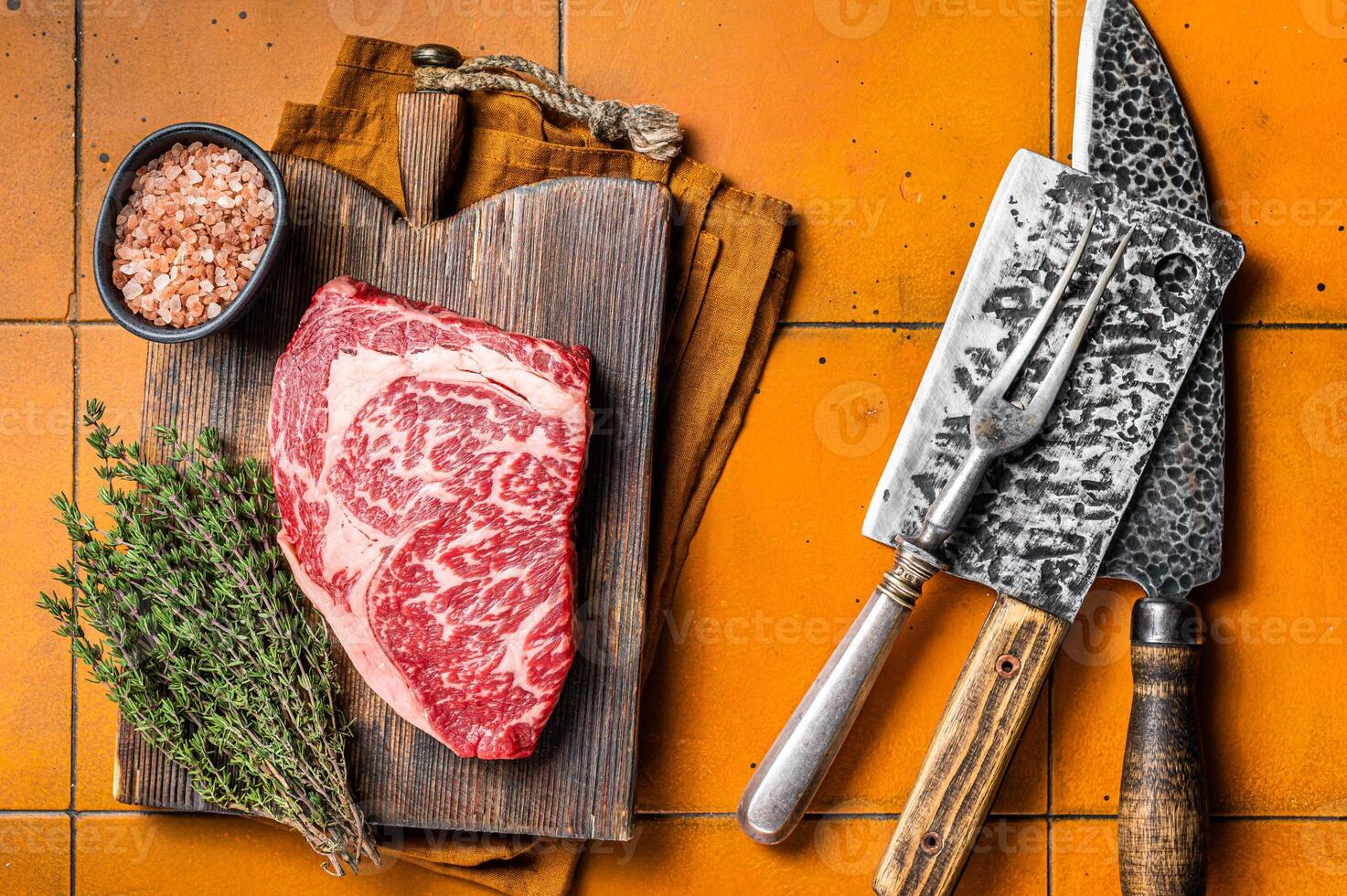 Prime Raw wagyu Rib Eye beef meat steak on wooden board. Orange background. Top view photo