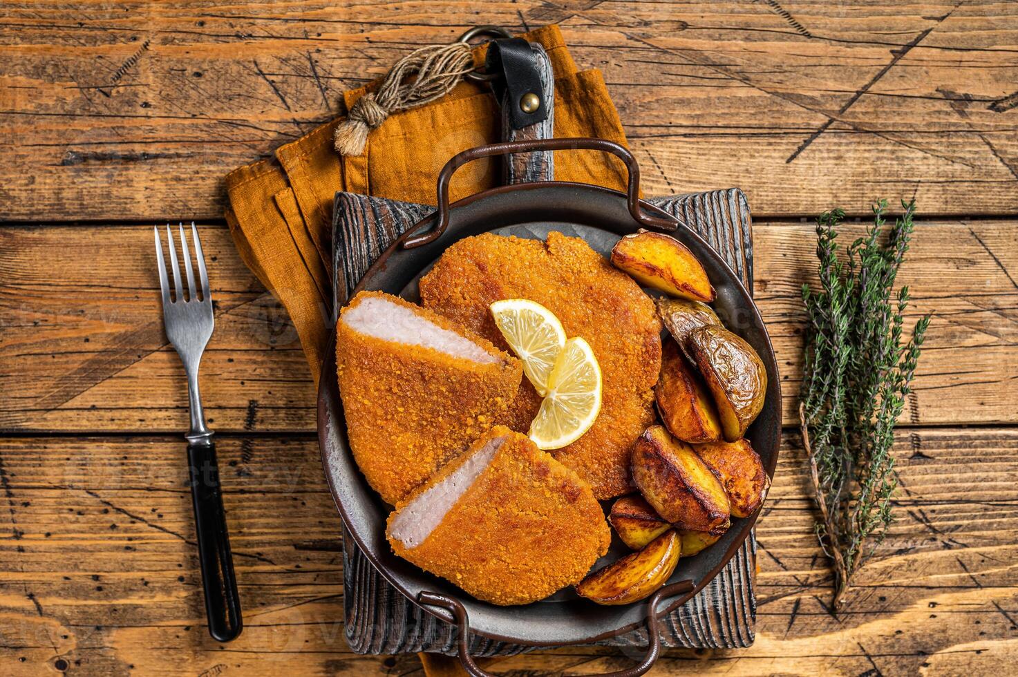 Delicious crispy pork schnitzel with fried potato wedges. Wooden background. Top view photo