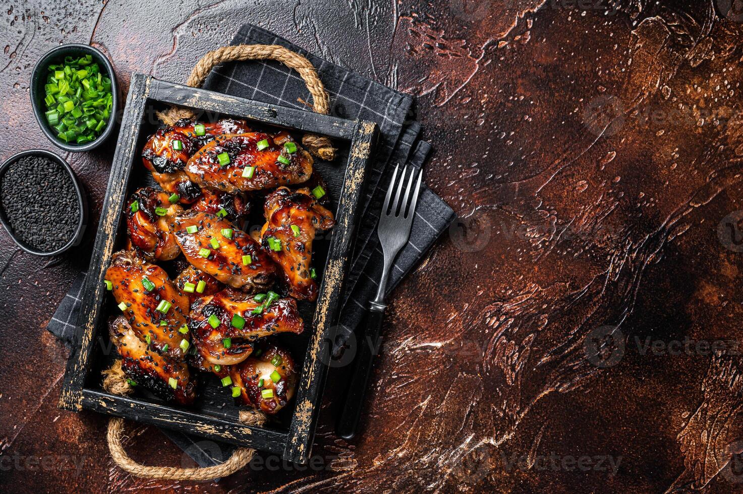 BBQ Chicken wings in Teriyaki sauce with black sesame in a tray. Gray background. Top view. Copy space photo