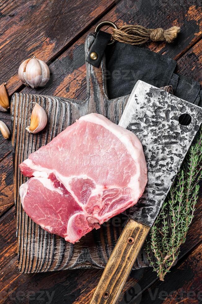 Butcher cutting board with Raw T-bone pork chop meat steak. Wooden background. Top view photo