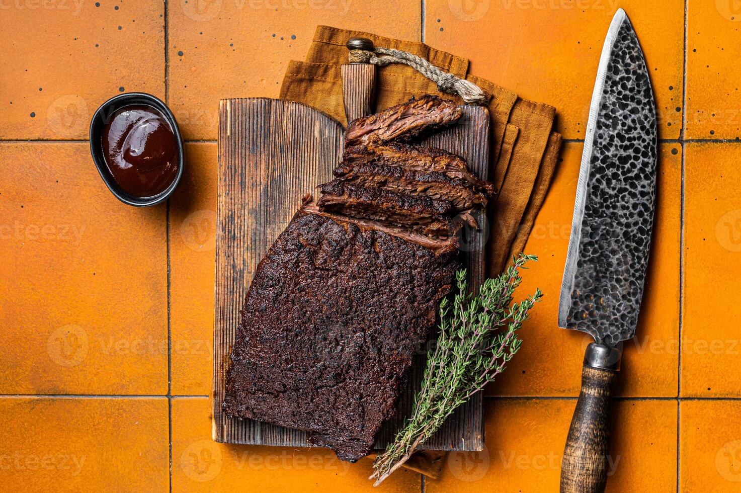 Smoked Barbecue Beef Brisket with Sauce on wooden board. Orange background. Top view photo