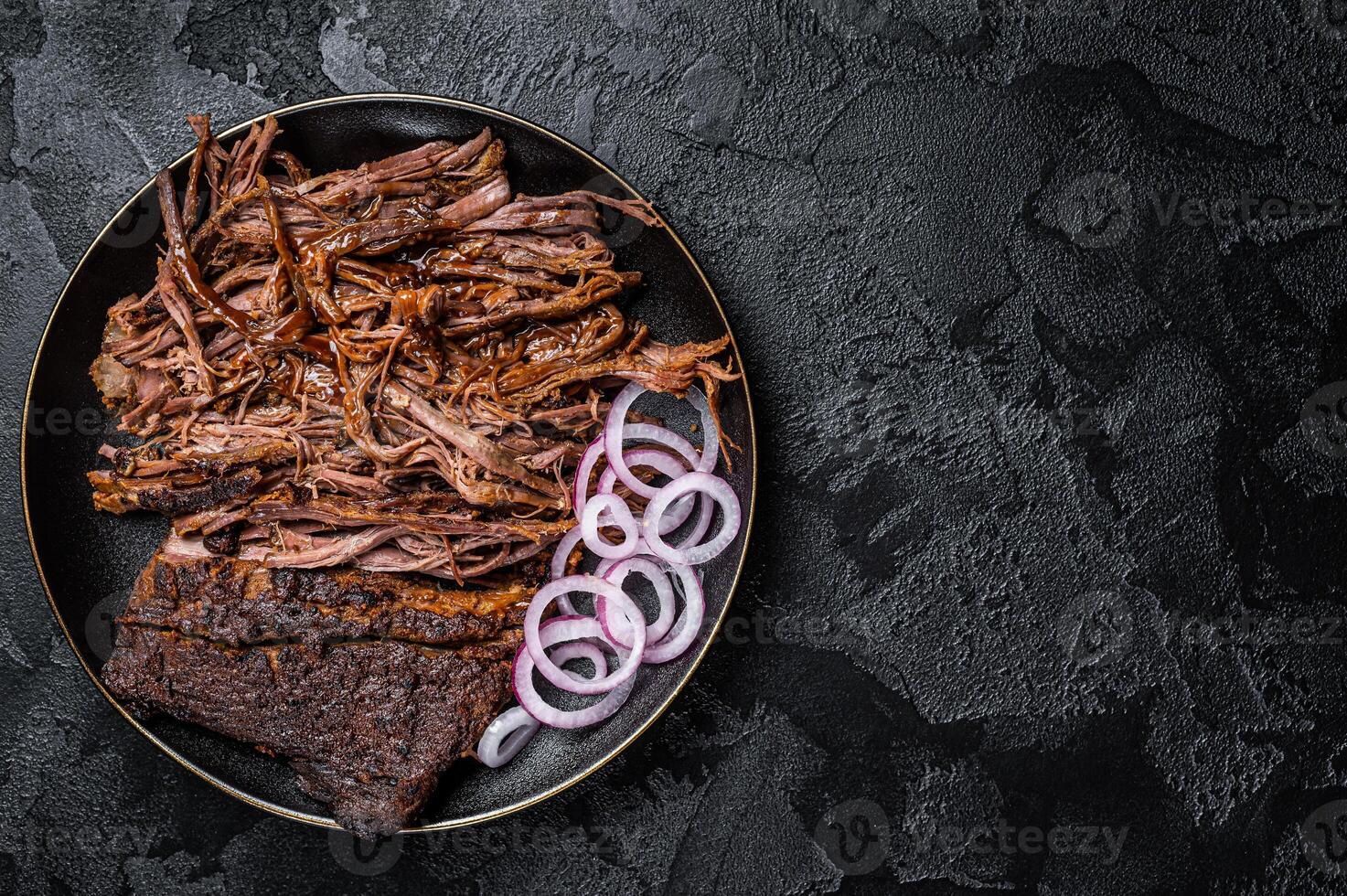 BBQ pulled pork meat on plate. Black background. Top view. Copy space photo