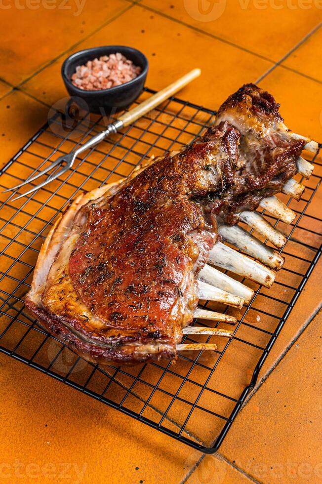 Roast Rack of lamb ribs, spareribs on grill. Orange background. Top view photo