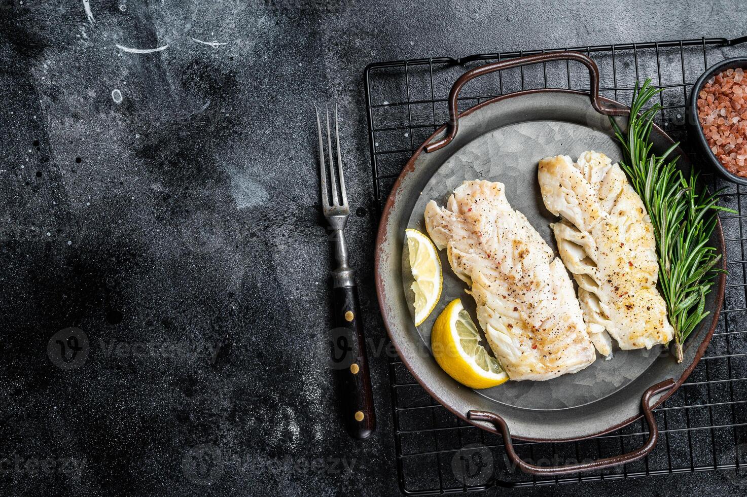 Roast Fillets of codfish, cooked cod fish meat. Black background. Top view. Copy space photo