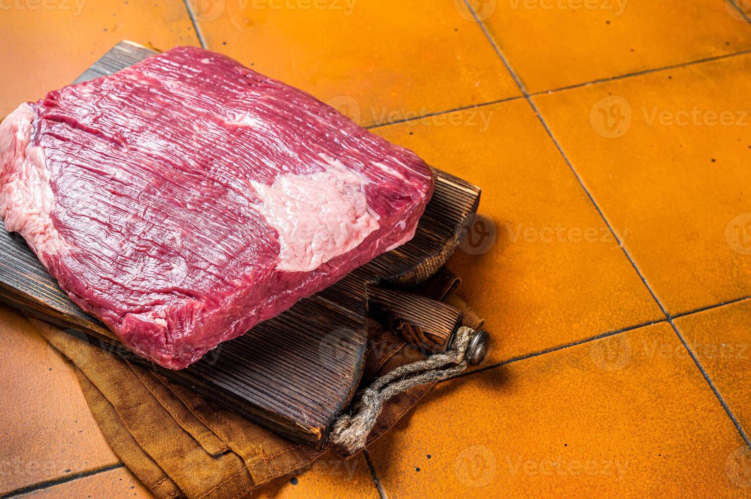 Whole piece of raw Beef Brisket meat. Orange background. Top view. Copy space photo