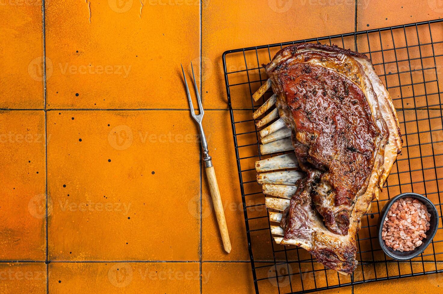 Roast Rack of lamb ribs, spareribs on grill. Orange background. Top view. Copy space photo