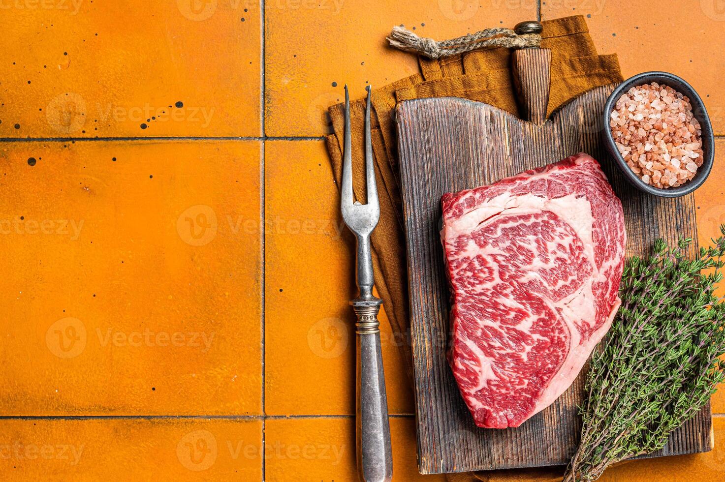 Prime Raw wagyu Rib Eye beef meat steak on wooden board. Orange background. Top view. Copy space photo