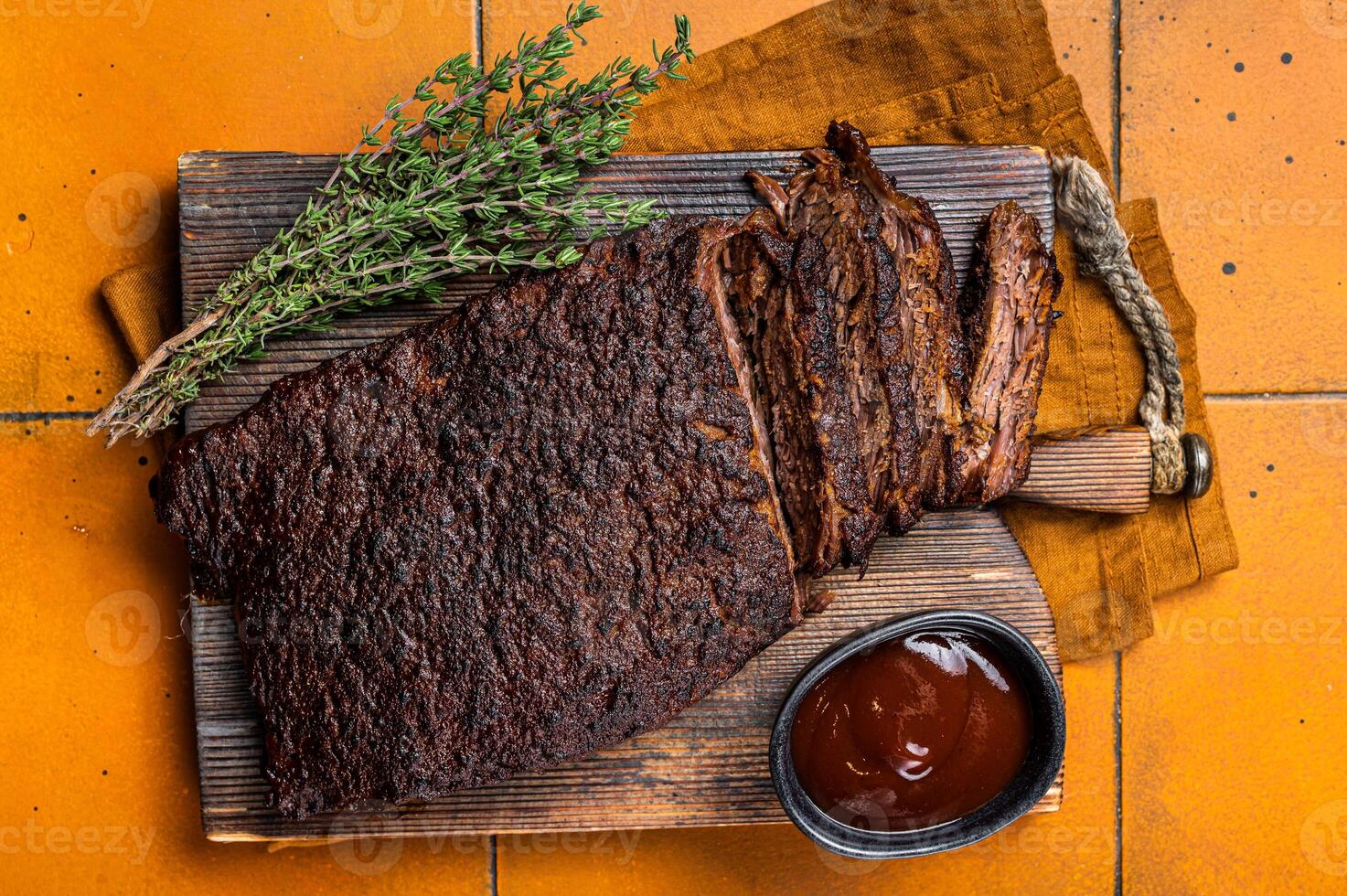 Smoked Barbecue Beef Brisket with Sauce on wooden board. Orange background. Top view photo