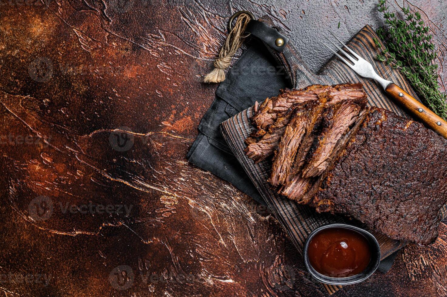 Traditional smoked barbecue wagyu beef brisket on wooden board. Dark background. Top view. Copy space photo