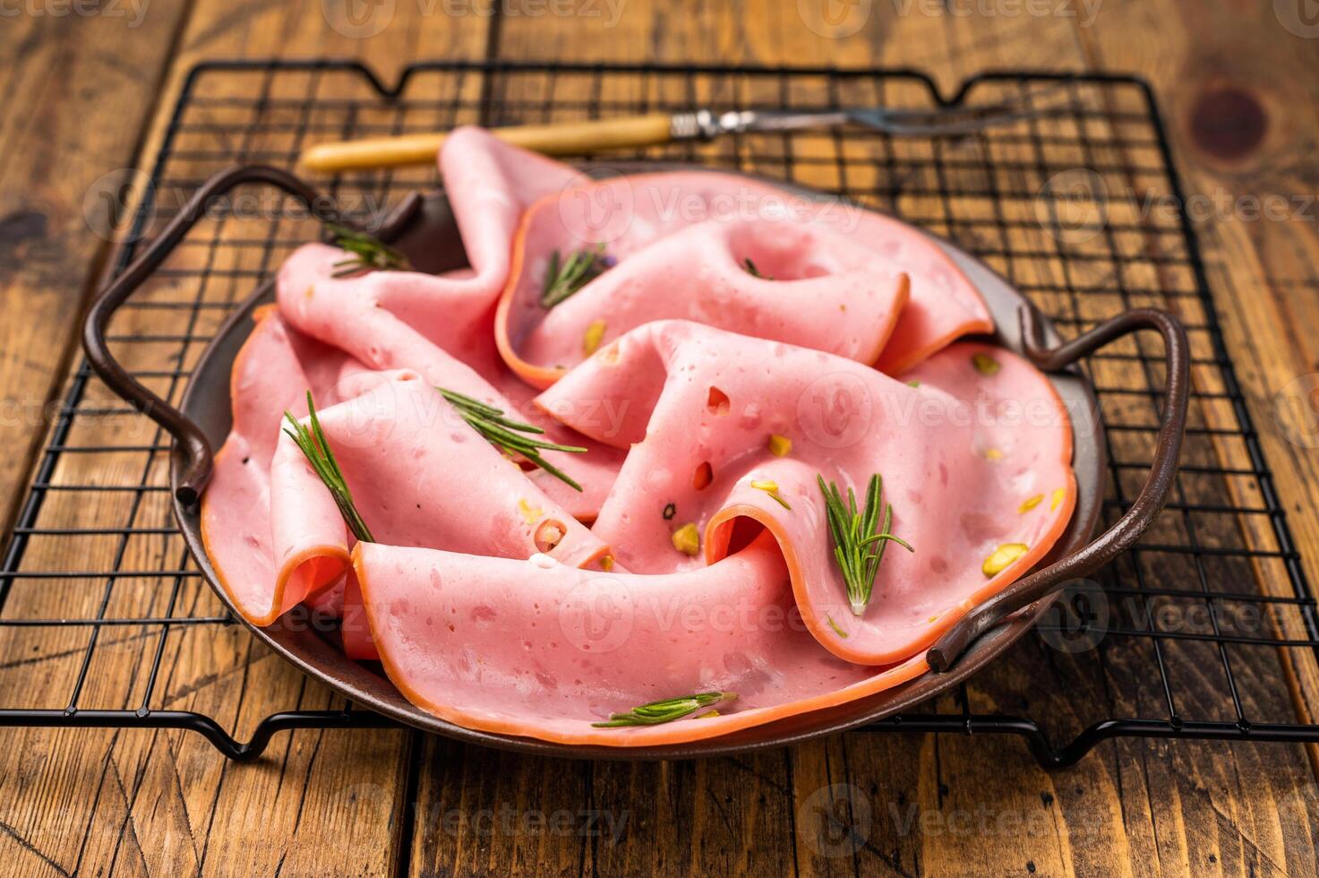 Mortadella sausage slices with pistachios for sandwiches in steel tray. wooden background. top view photo