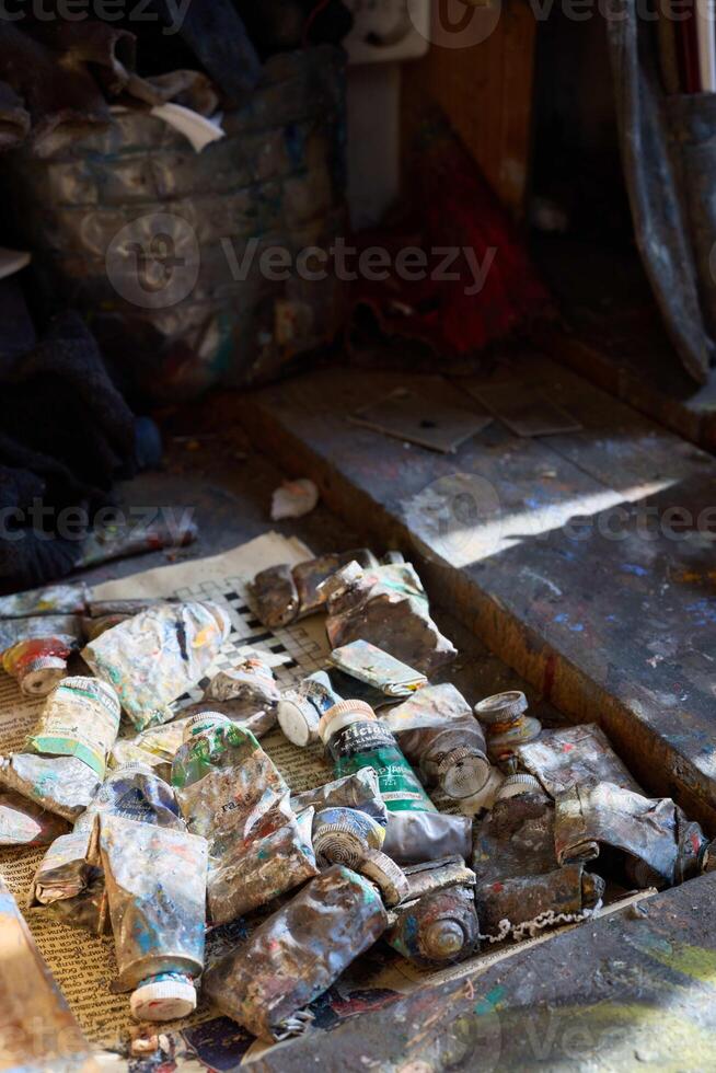 Artist's workspace with various paint tubes and materials organized on a wooden table photo