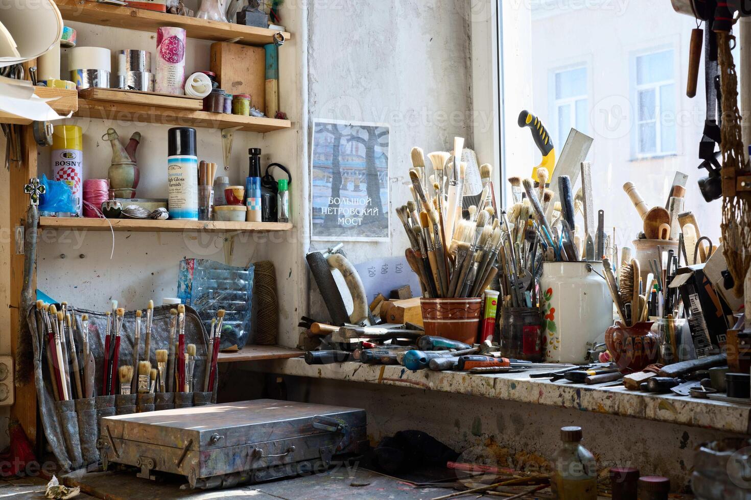 Creative workspace filled with various tools and brushes in a sunlit studio setting photo