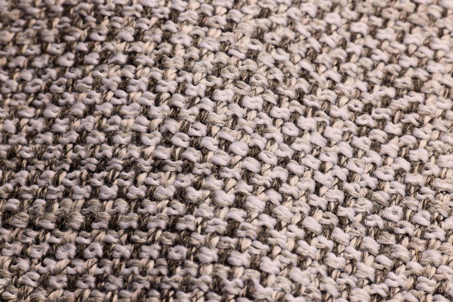 A closeup of a textured beige knitted fabric highlights its intricate detail and craftsmanship photo