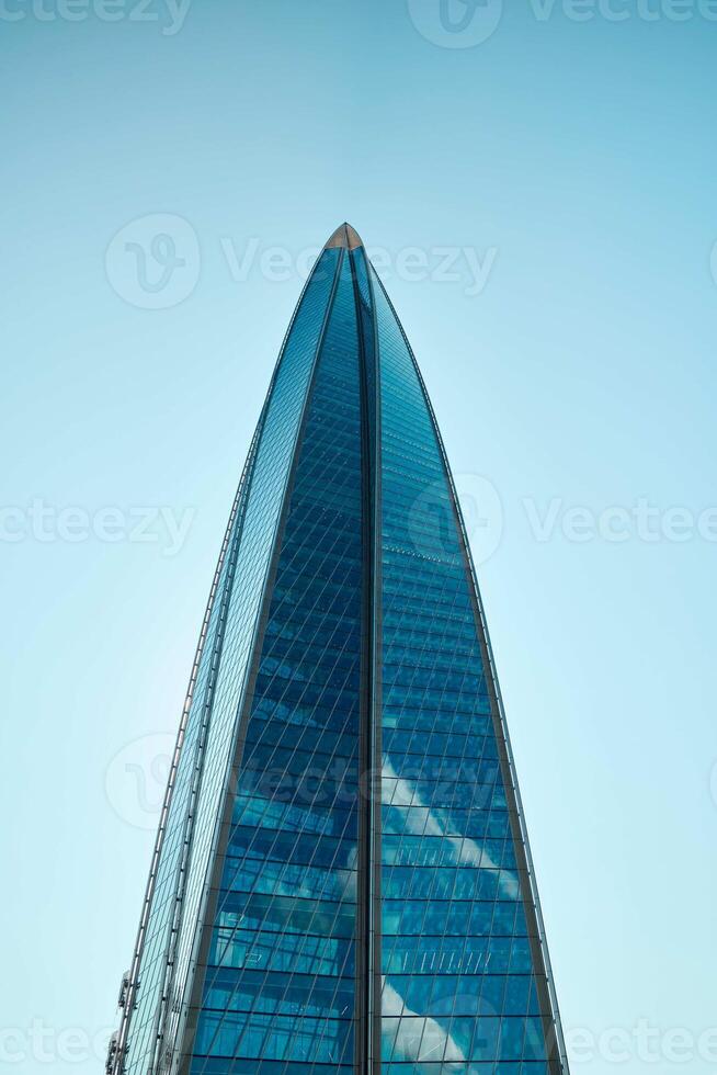 A stunning modern skyscraper stands tall against a clear, cloudless blue sky above photo